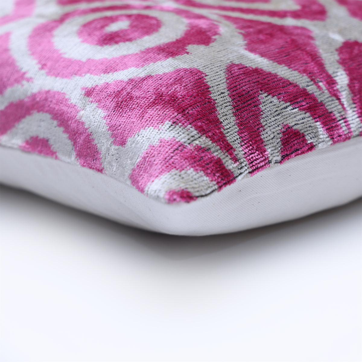 Corner close-up of fuchsia pink ikat velvet, seam detail and silvery white backing