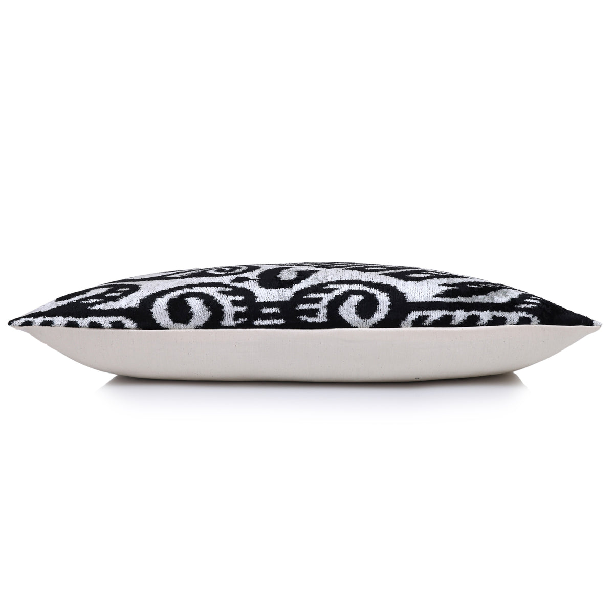 Side profile of a silvery white and jet black lumbar pillow showing depth