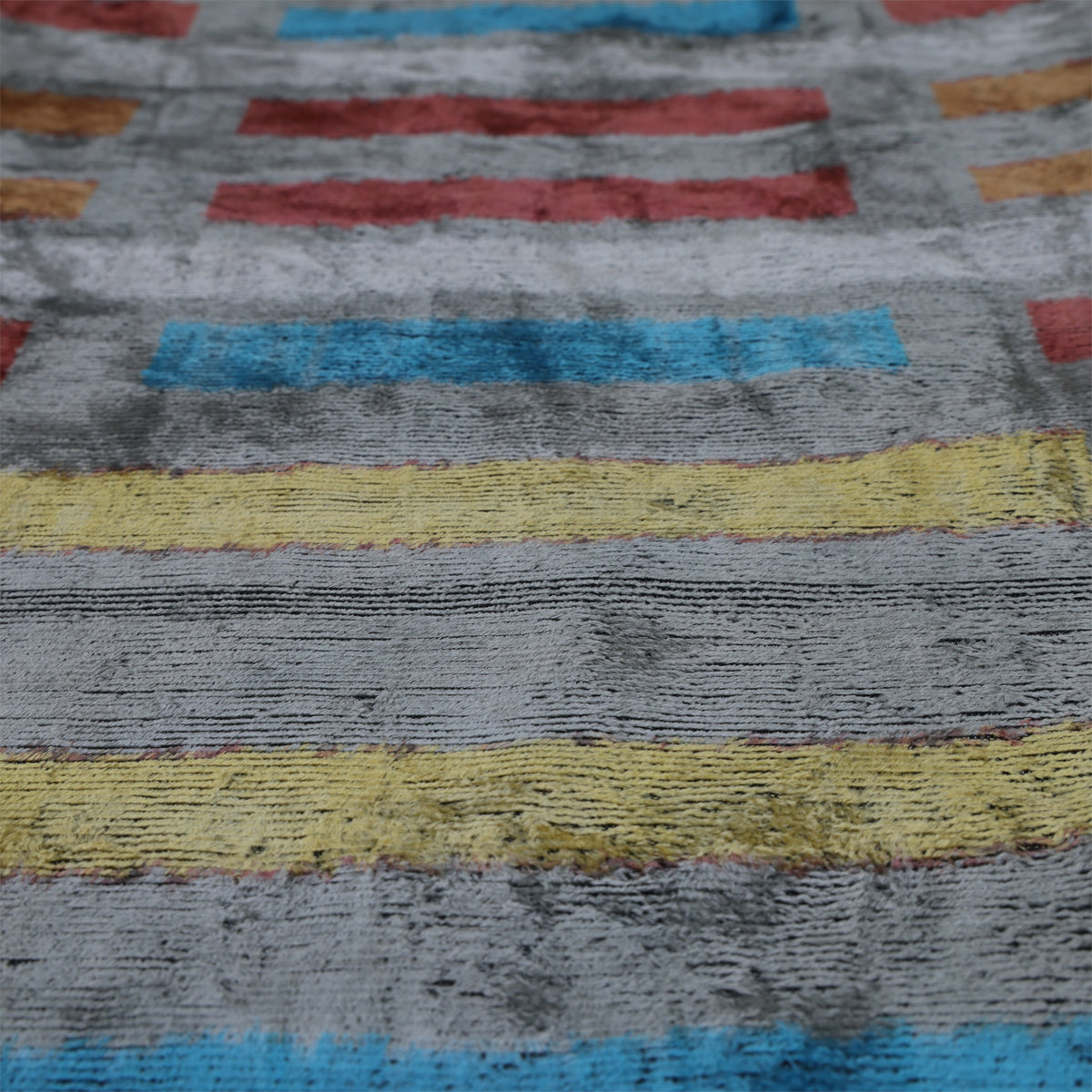 Low-angle view across silver gray geometric striped and block-patterned velvet