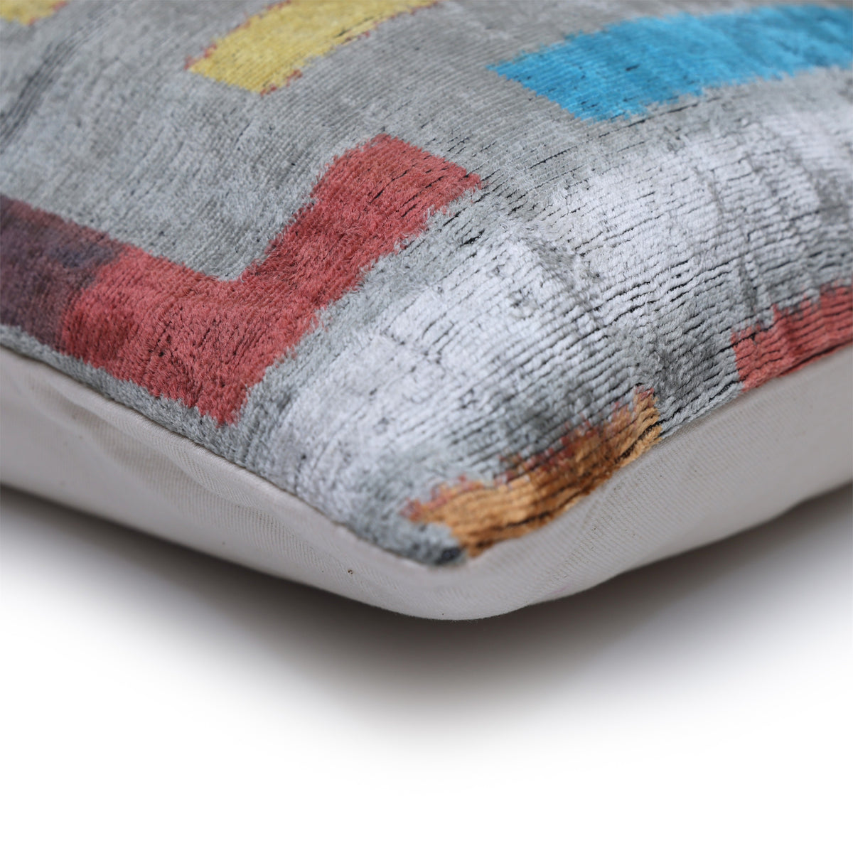 Corner detail of silver gray patterned velvet, seam and solid linen backing