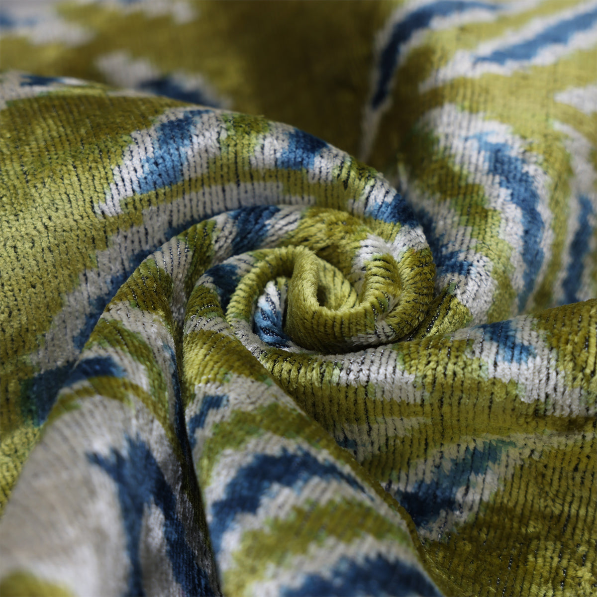 Close-up swirl fold showing olive chartreuse green ikat velvet pile and sheen