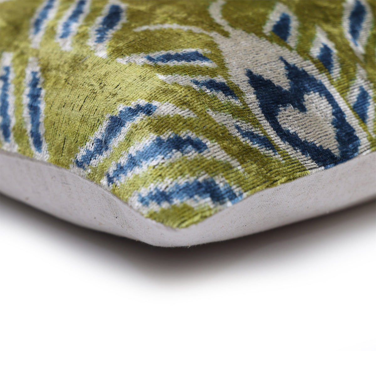 Corner detail of olive chartreuse green ikat front beside plain linen backing