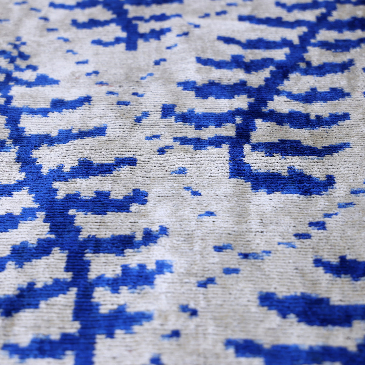 Close view of cobalt blue and silver gray botanical fern pattern on silk velvet