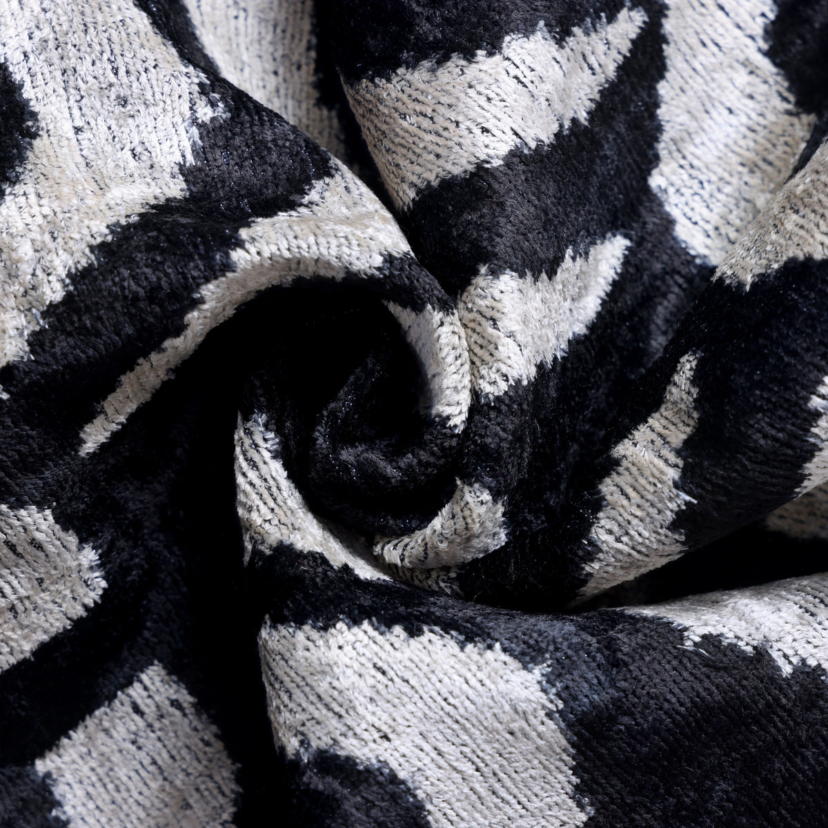 Close-up of an inky black spiral swirl within the ivory velvet textile