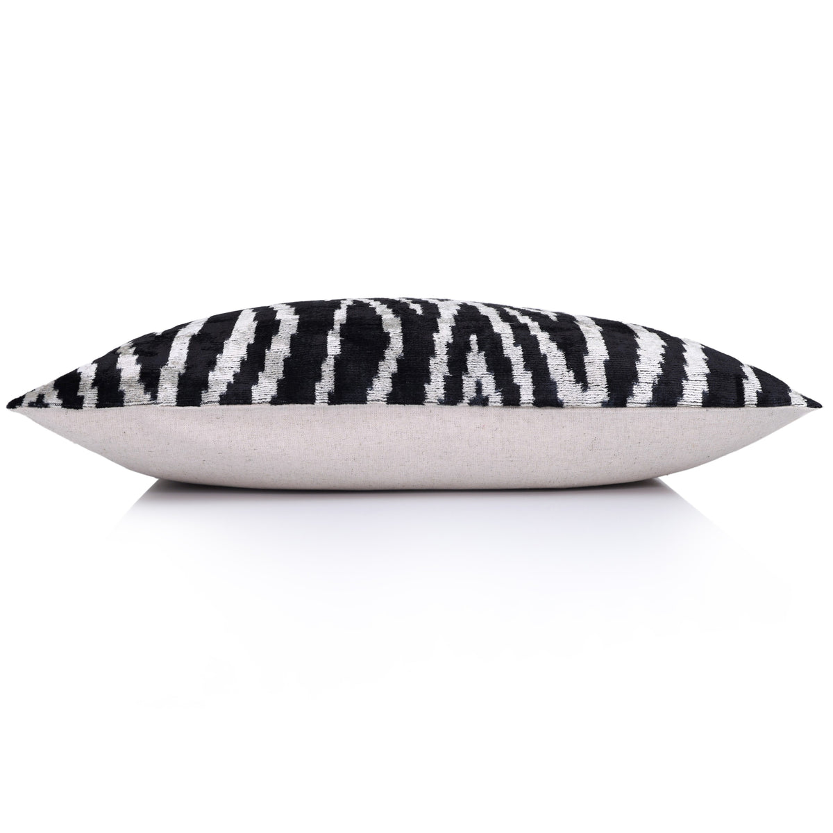 Side profile of square ikat velvet pillow showing the linen backing fabric