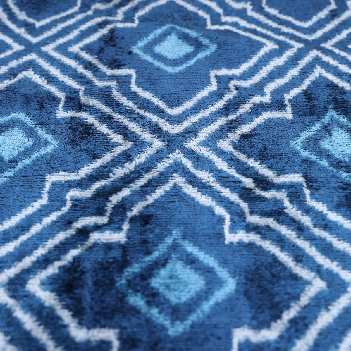 Macro view across blue and white velvet diamond pattern with blurred ikat edges