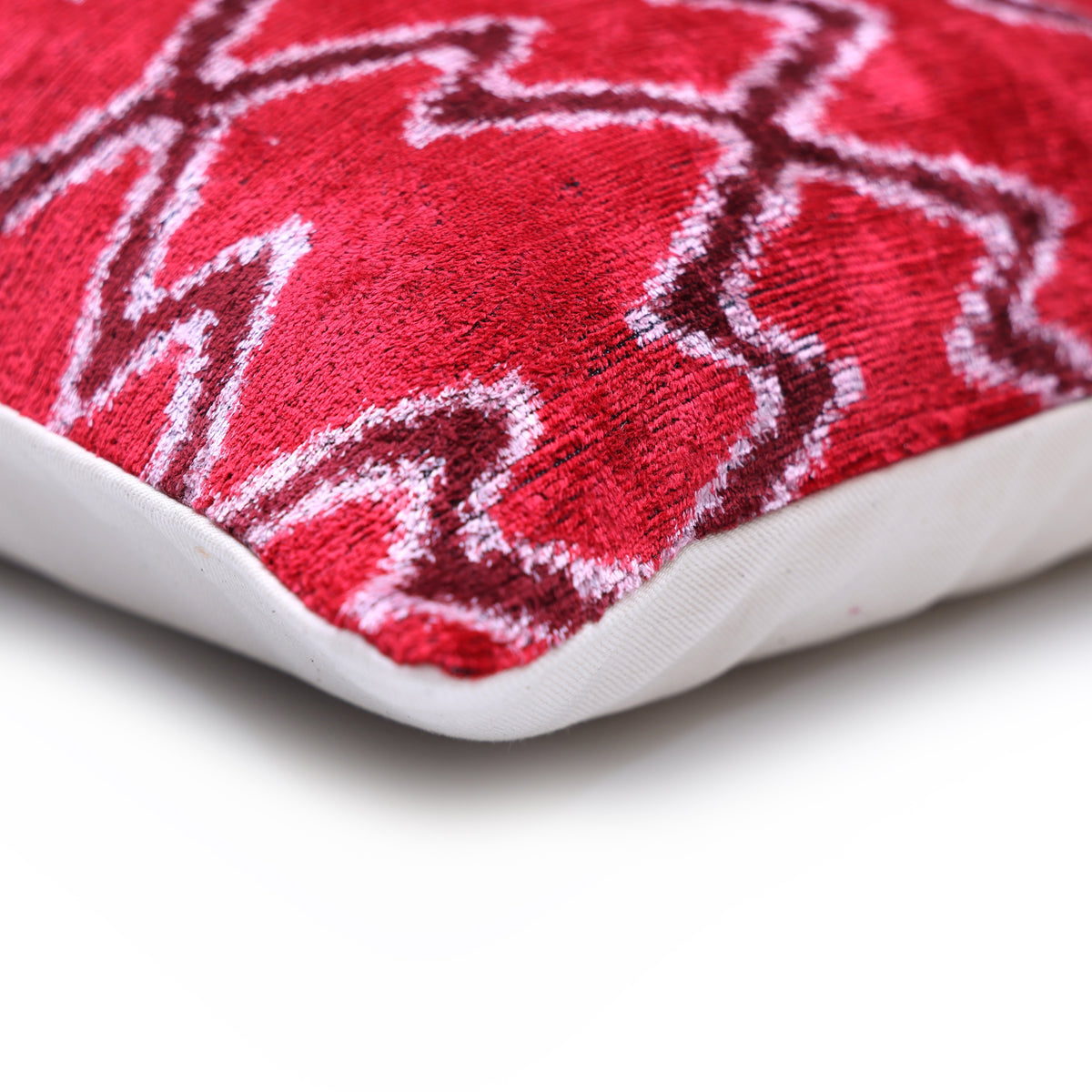 Lumbar pillow corner showing cherry red velvet front and neutral linen backing