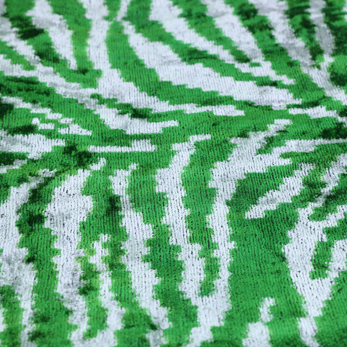 Close-up of plush velvet cut pile forming emerald green and cool white zebra stripes.