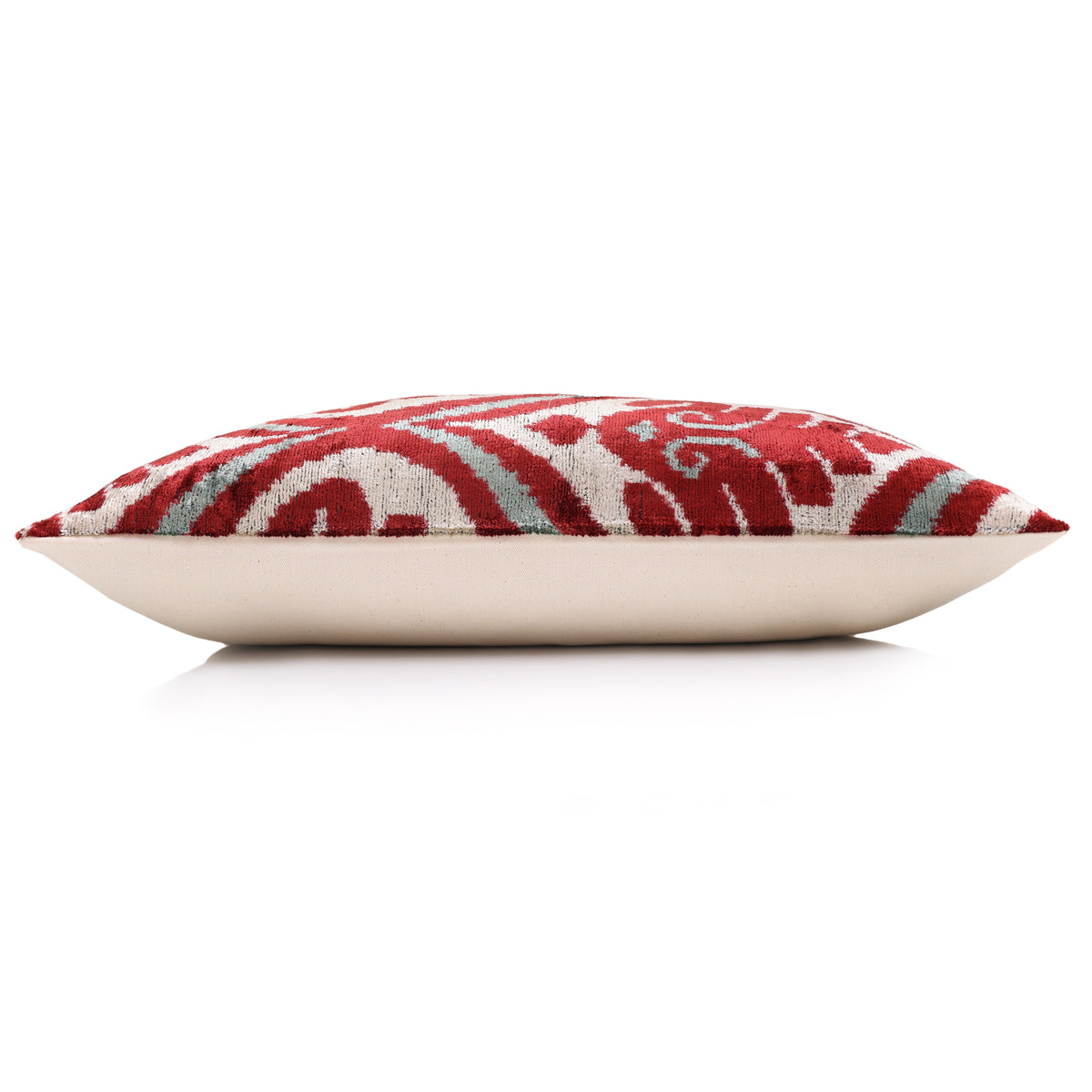 Side profile of the crimson and ivory ikat lumbar pillow showing its backing