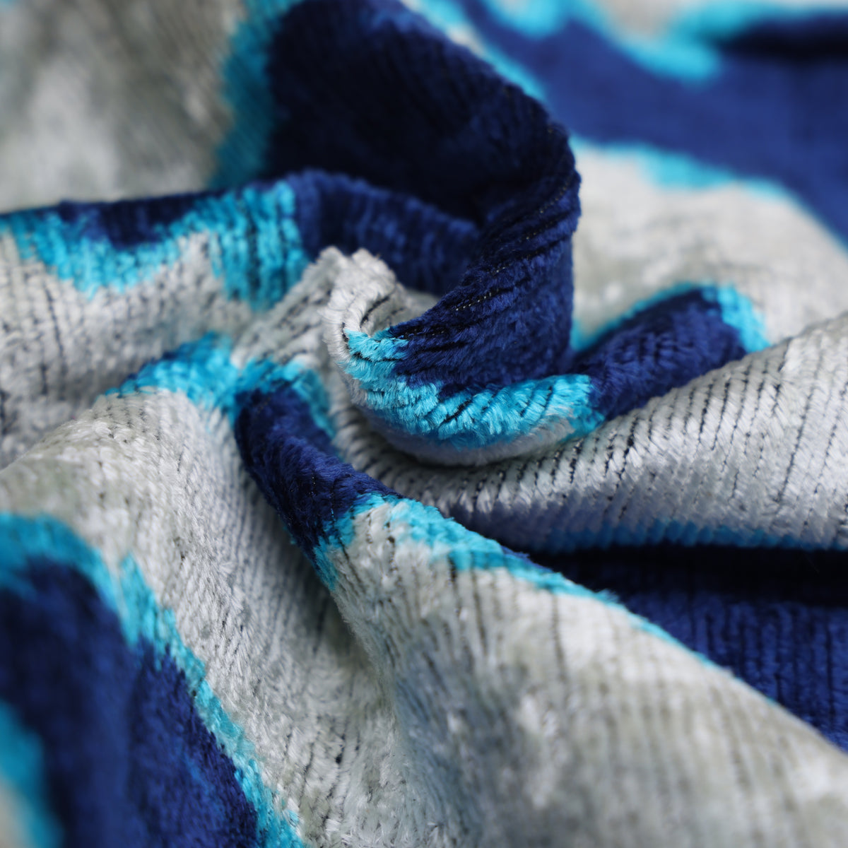 Folded silk velvet pile showing shifting sheen in silvery white and blue