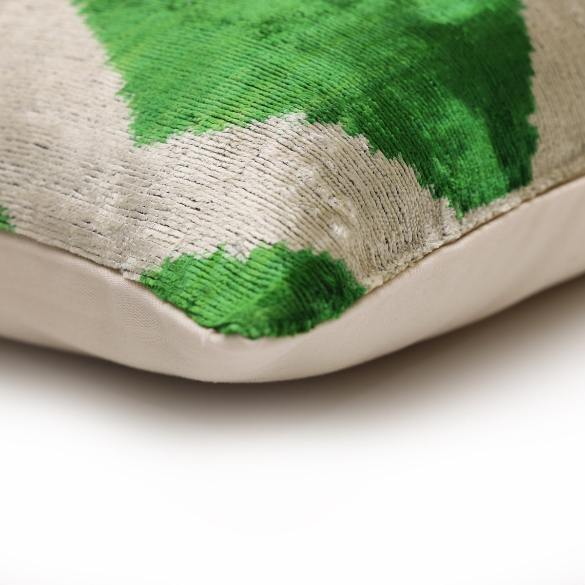 Pillow corner showing emerald green and pale greige pattern, seam detail and linen backing