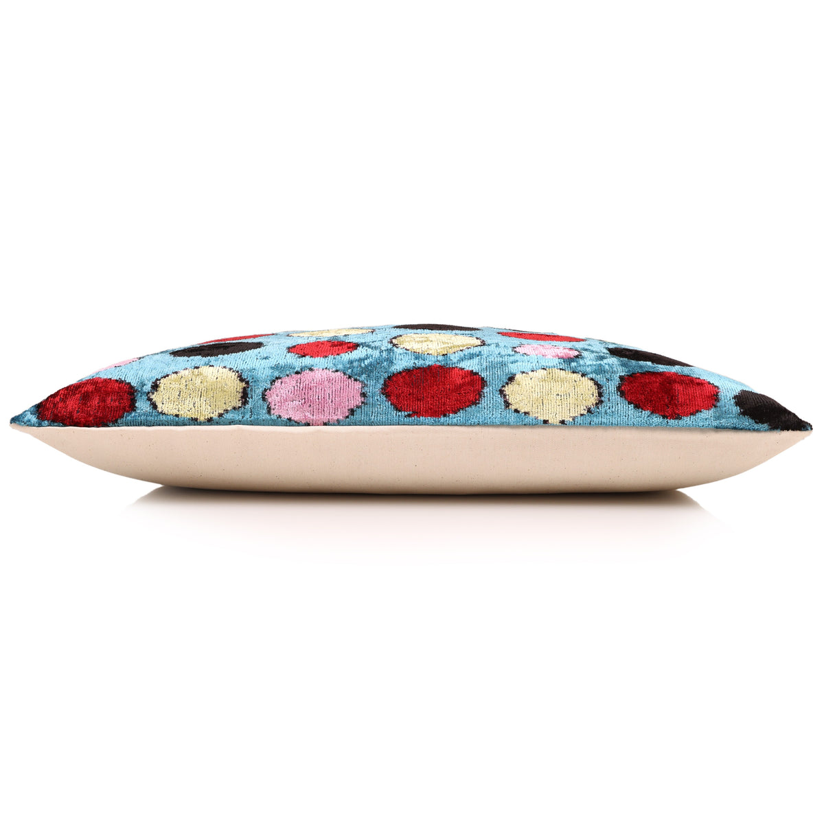 Side profile of the cerulean blue polka dot lumbar pillow with light neutral backing