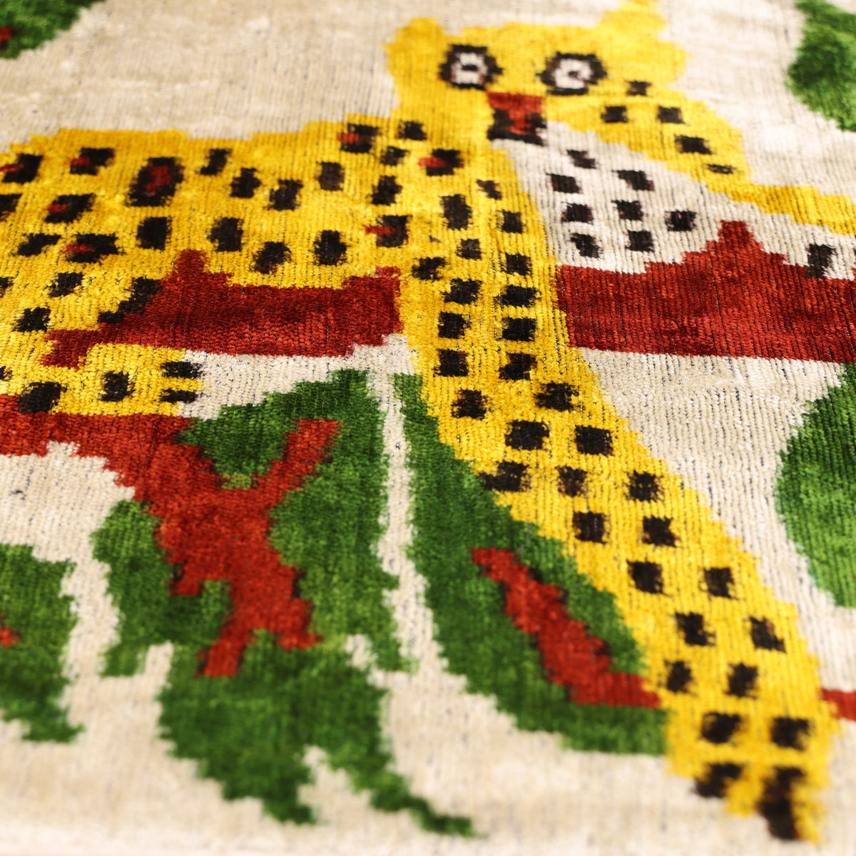 Angled detail of leopard face, body and forest green foliage on velvet