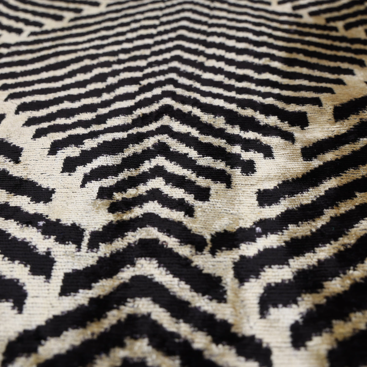Low-angle detail of jet black and champagne beige chevron pattern across the velvet surface