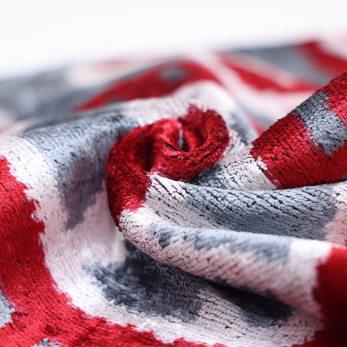 Low-angle view of crimson red and slate gray velvet folds with visible sheen