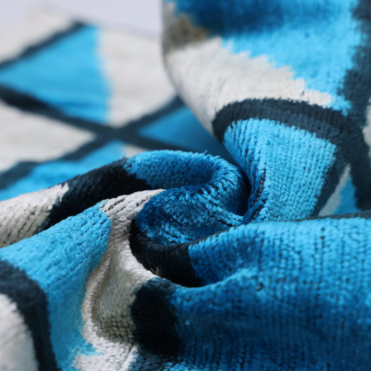 Gathered cerulean blue and silvery off-white velvet showing plush texture