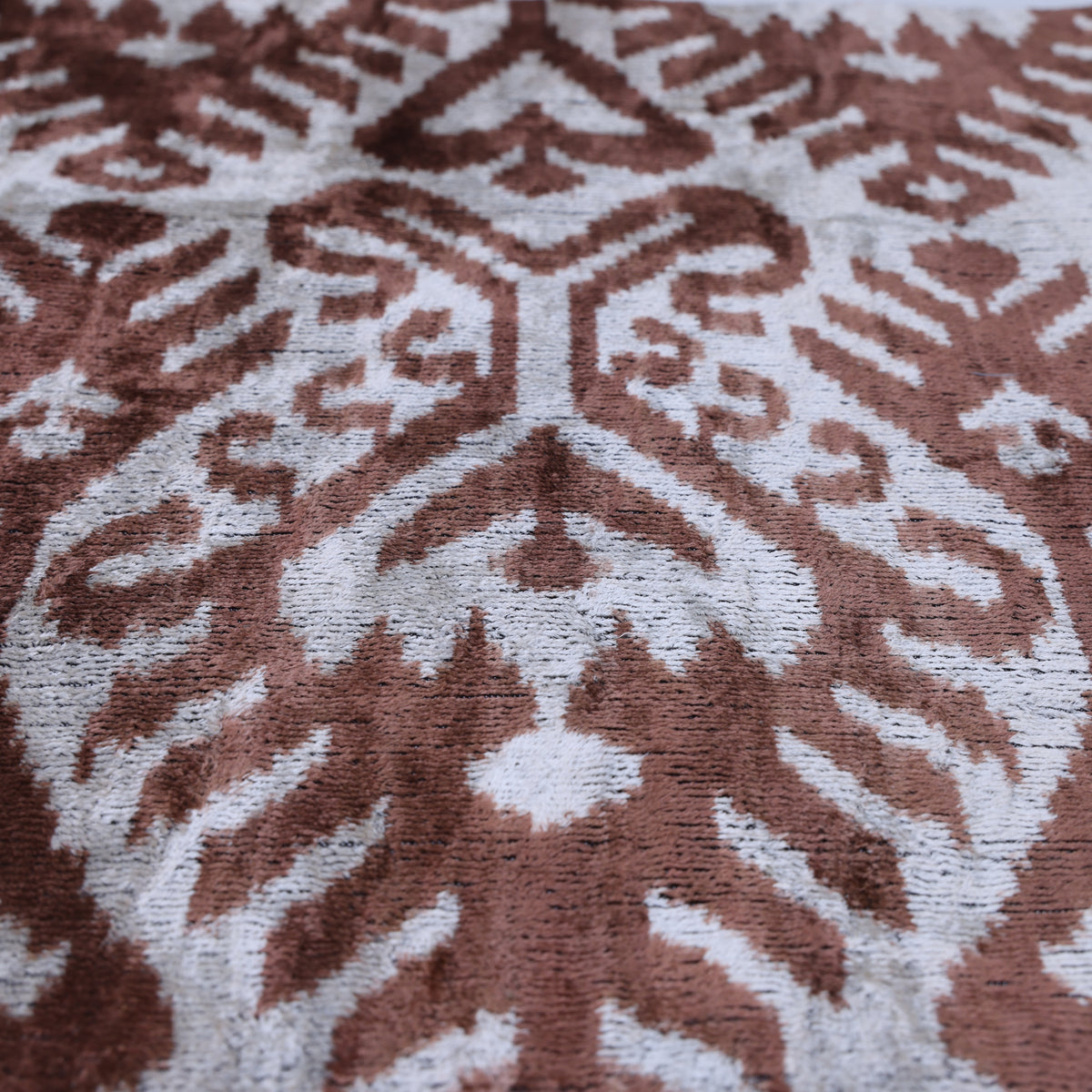 Angled close-up of warm brown and silvery white ikat pattern and velvet pile