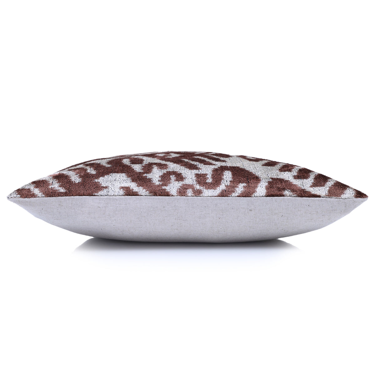 Side profile of warm brown and silvery white velvet pillow with plain backing