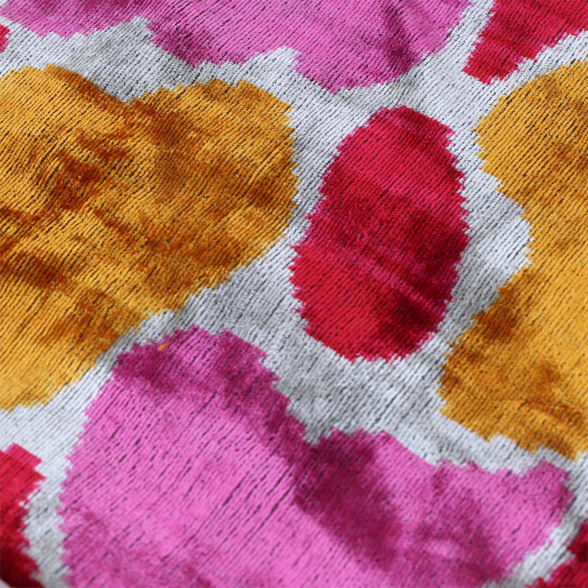 Overhead detail of fuchsia pink, marigold yellow and silvery off-white velvet pattern