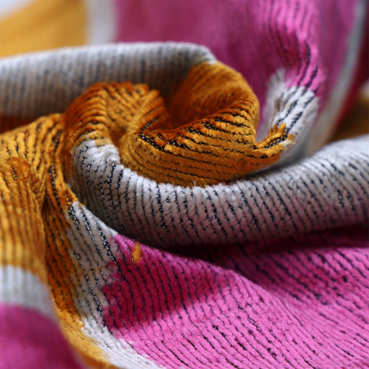 Macro view of marigold yellow velvet pile and painterly abstract ikat pattern