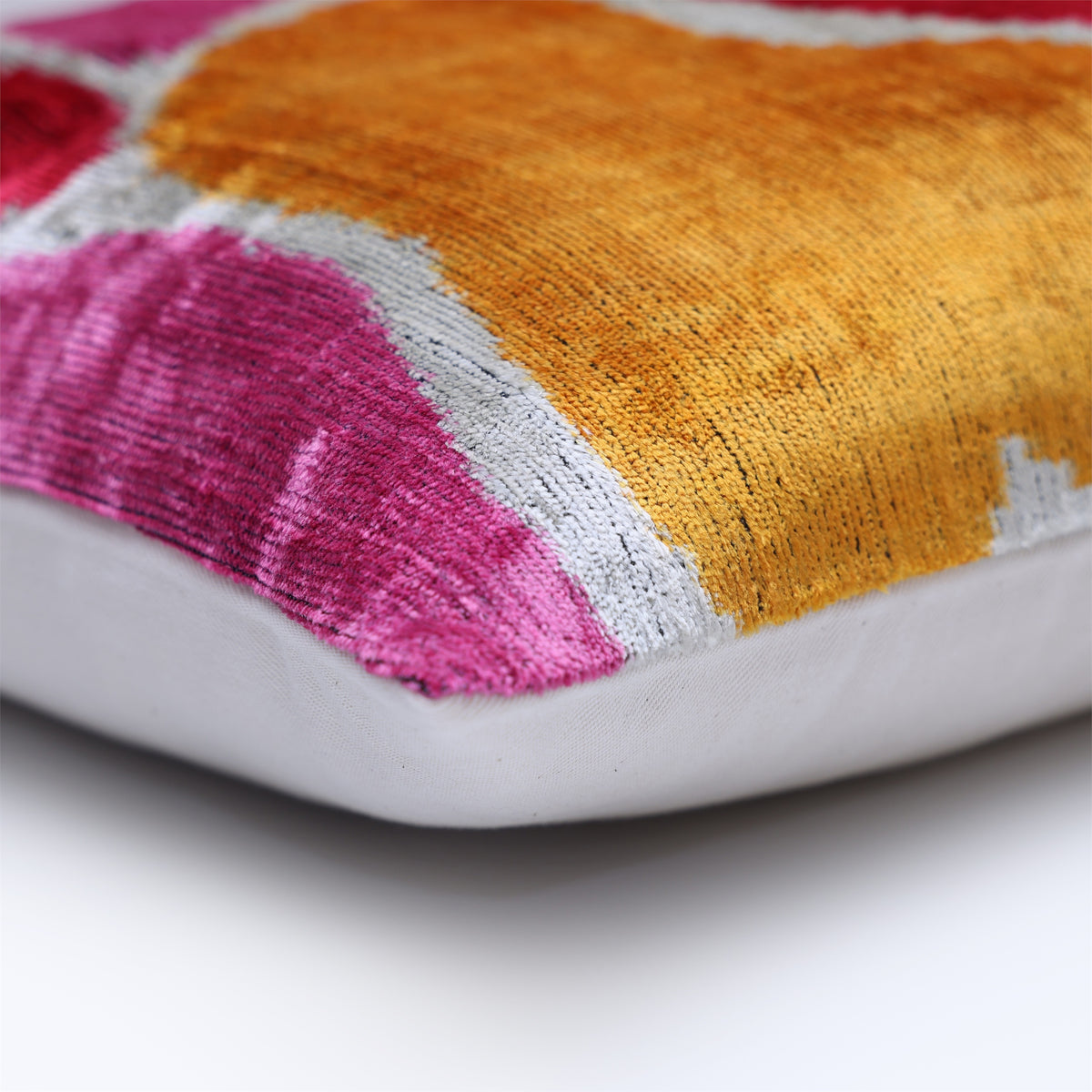 Corner detail of marigold yellow velvet seam with silvery off-white pattern and linen backing