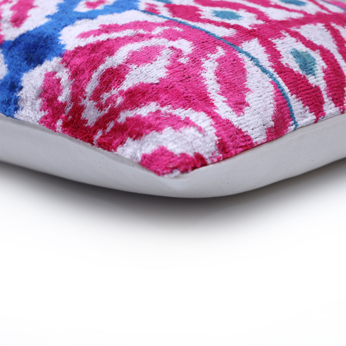 Lumbar pillow corner with magenta and white ikat front, seam and solid back