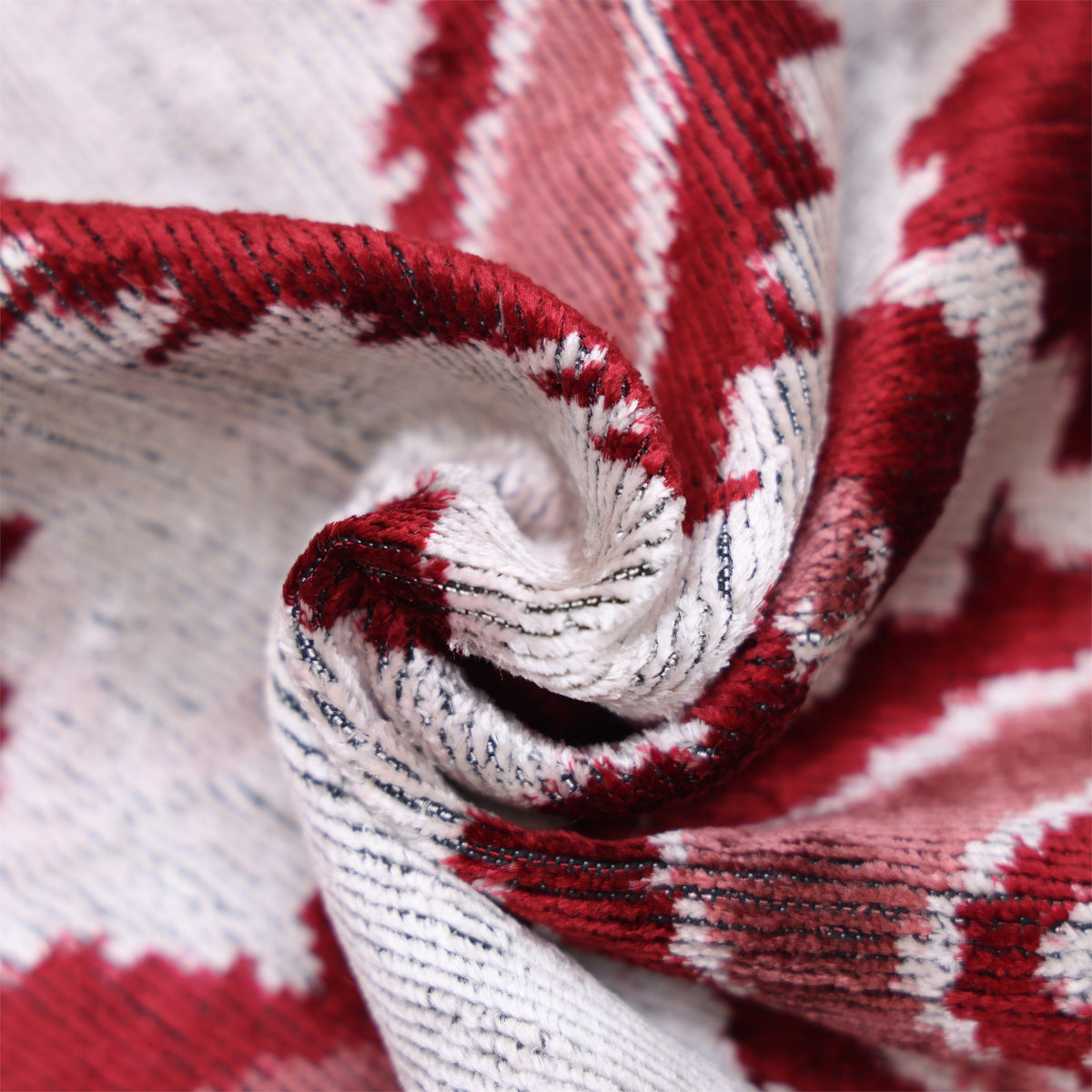 Close-up of silvery off-white and deep crimson red velvet folds showing luminous pile texture