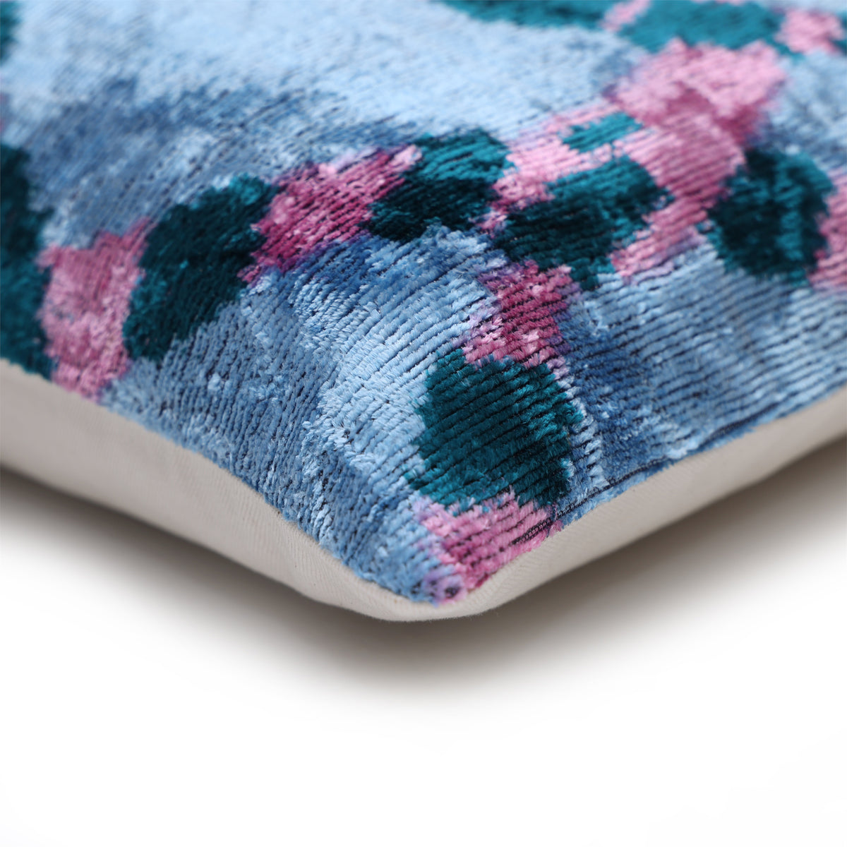 Lumbar pillow corner showing ice blue velvet edge and linen backing