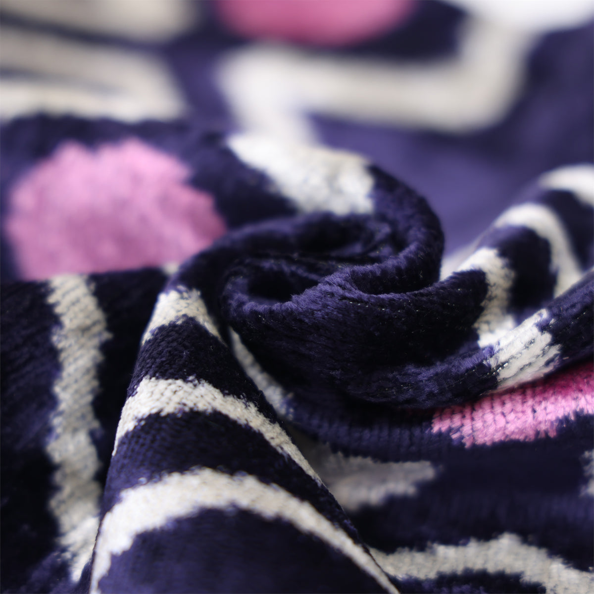 Macro view of a rolled deep indigo purple velvet fold with subtle silk sheen