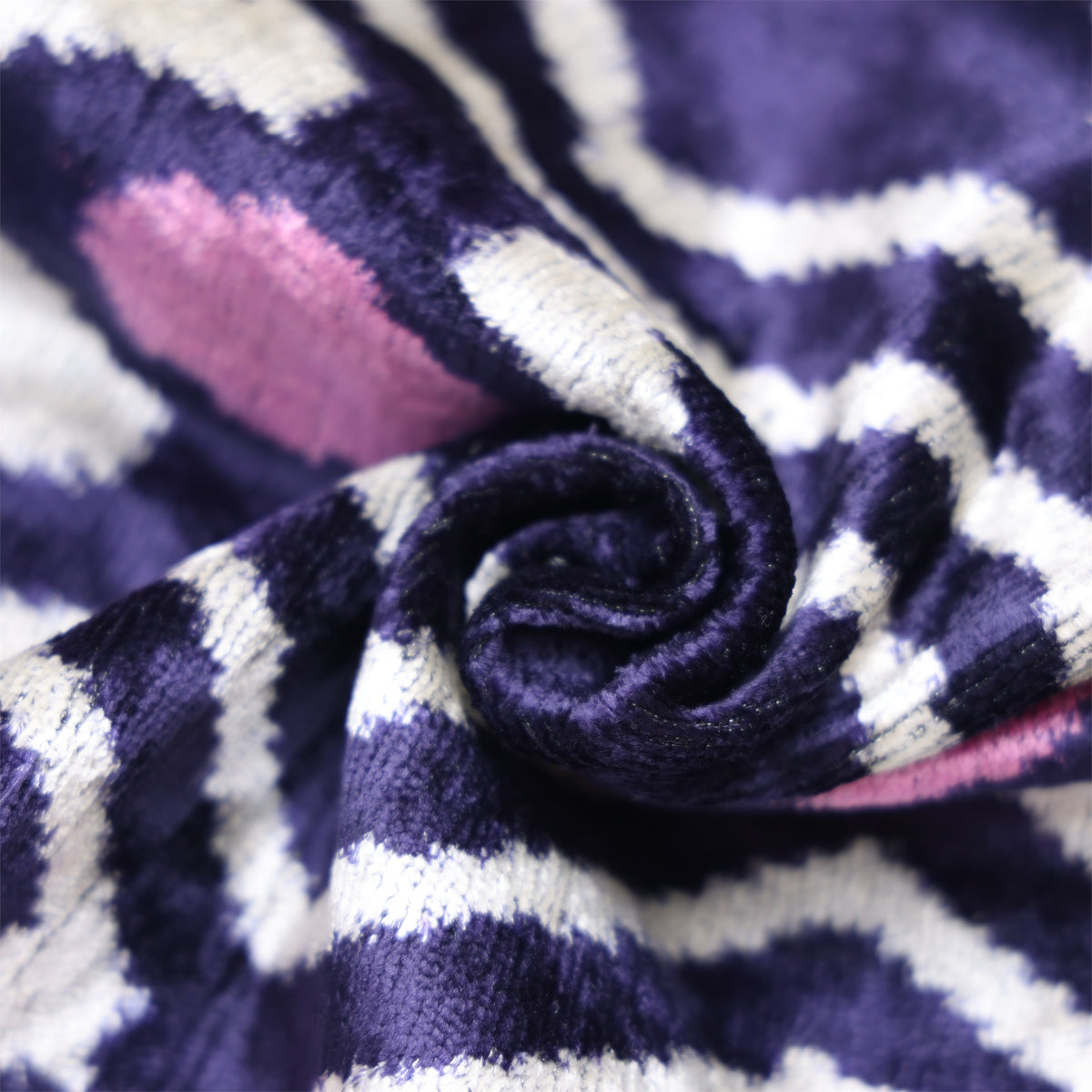 Close-up of deep indigo purple silk velvet pile with white and mauve pink geometric pattern