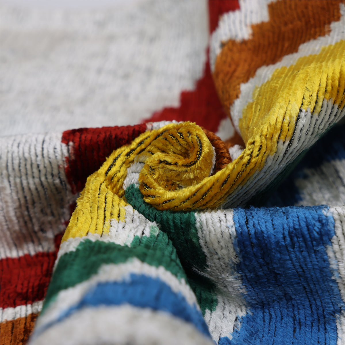 Macro view of gathered silk velvet showing silvery off-white and multicolor wave stripe texture
