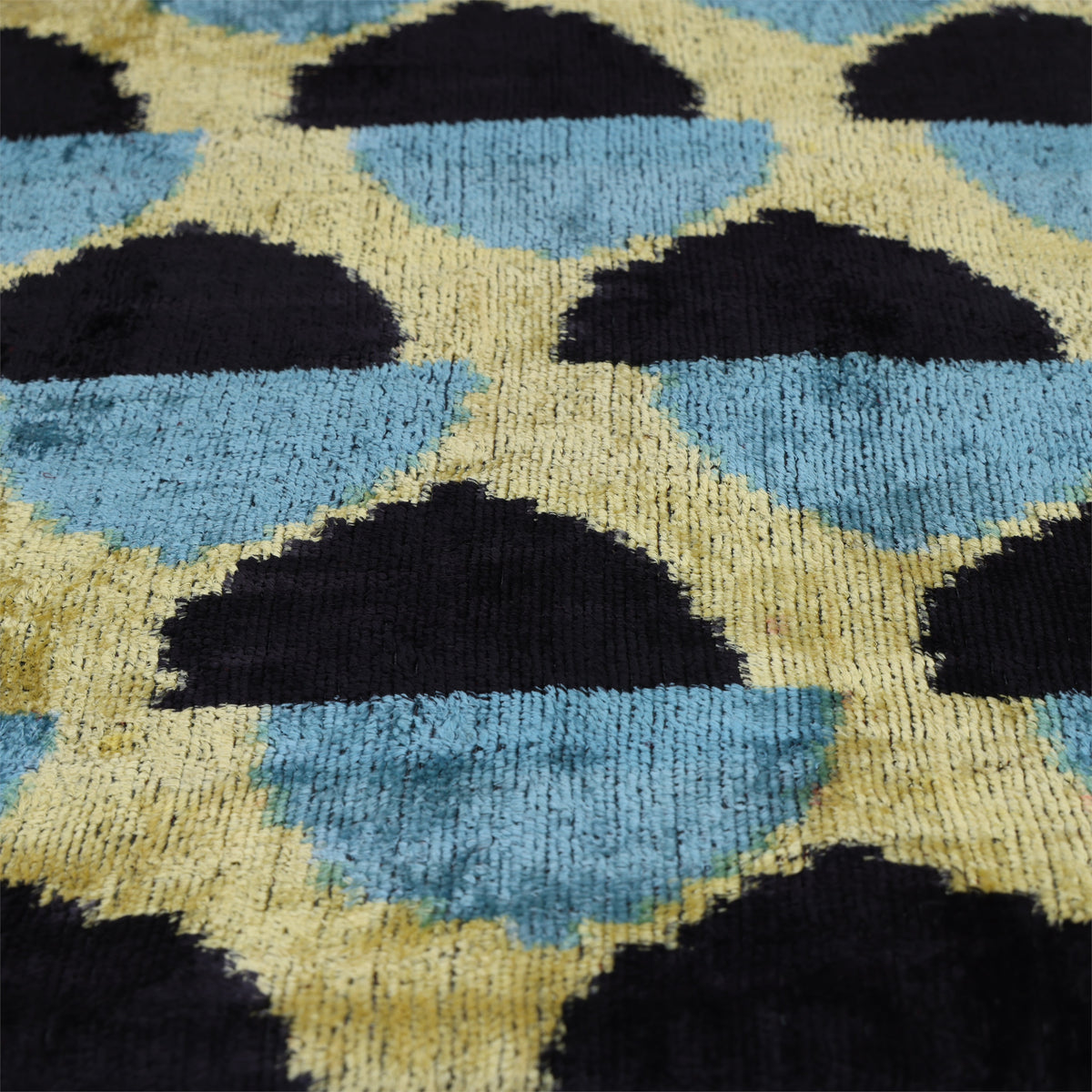 Low-angle view of black, slate blue and chartreuse yellow velvet pile and geometric pattern