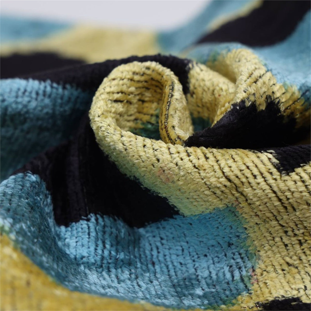 Macro view of silk velvet pile and woven geometric ikat detail in black, blue and yellow