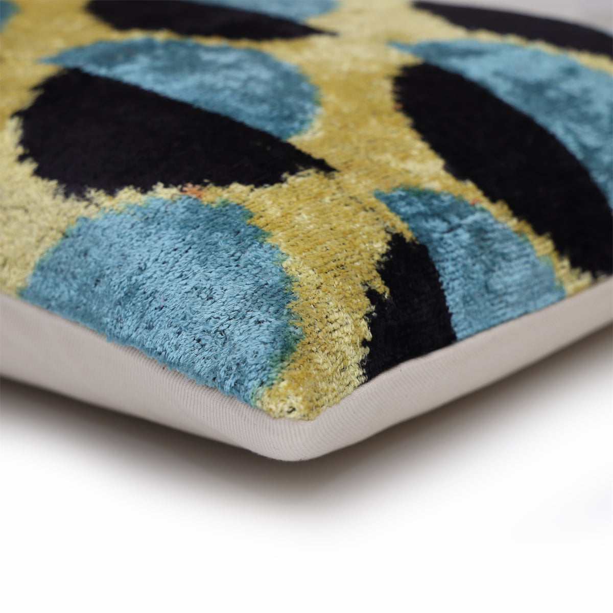 Corner profile of geometric velvet lumbar pillow showing seam and neutral linen backing