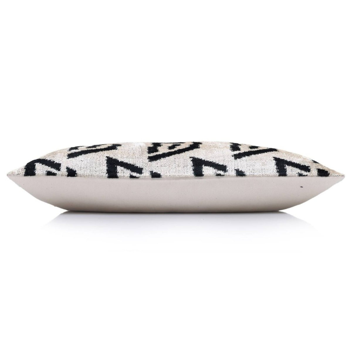 Side edge of geometric lumbar pillow showing plain fabric backing