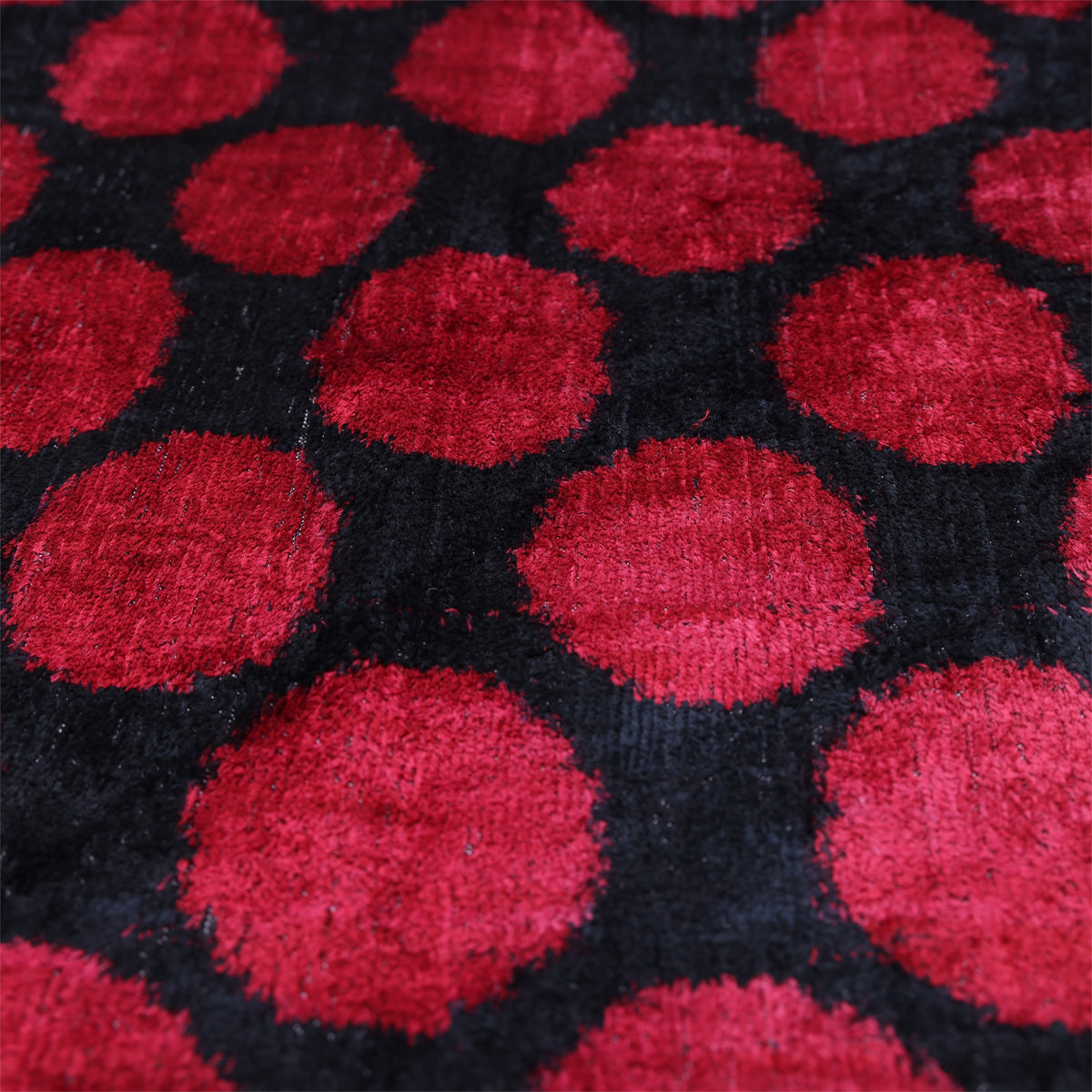 Angled close-up showing crimson red and black polka dots and plush velvet texture