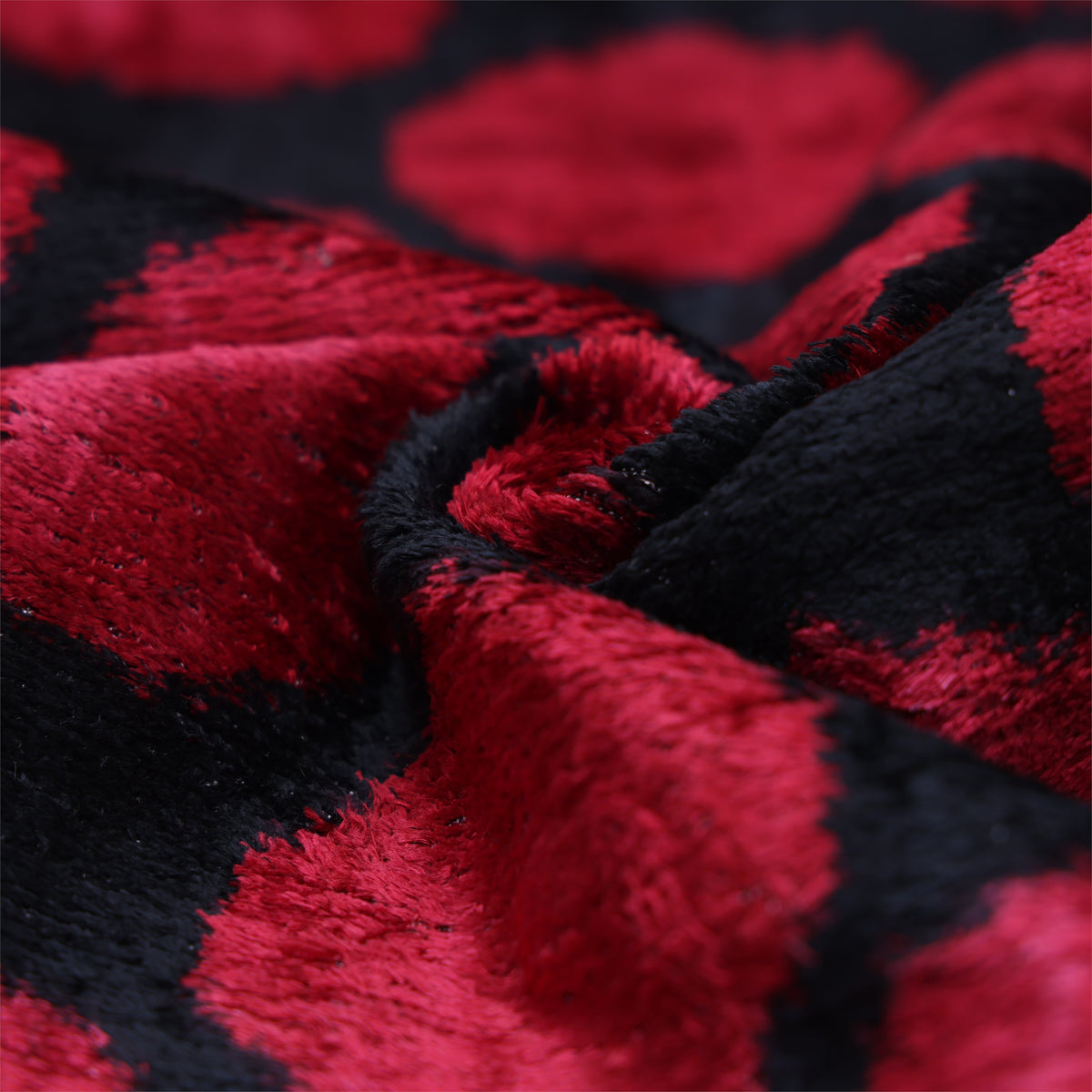 Low-angle close-up of folded crimson red and black silk velvet fabric