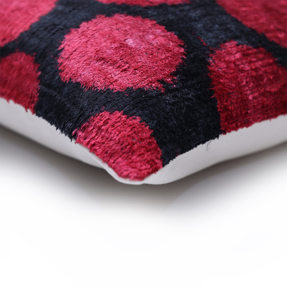 Corner close-up showing crimson red and black pillow seam and solid back