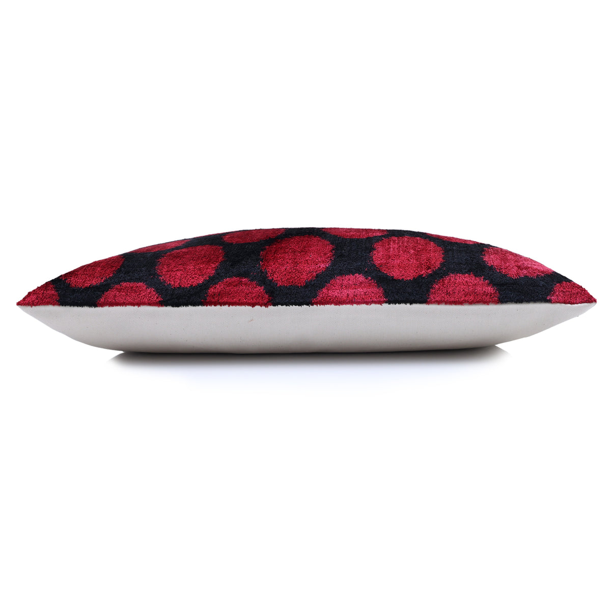 Side profile of crimson red and black polka dot lumbar pillow showing depth