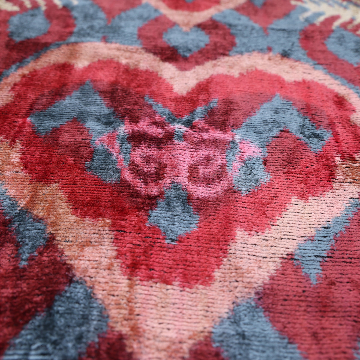 Macro view of the peach coral, mauve pink and light beige heart-shaped ikat motif