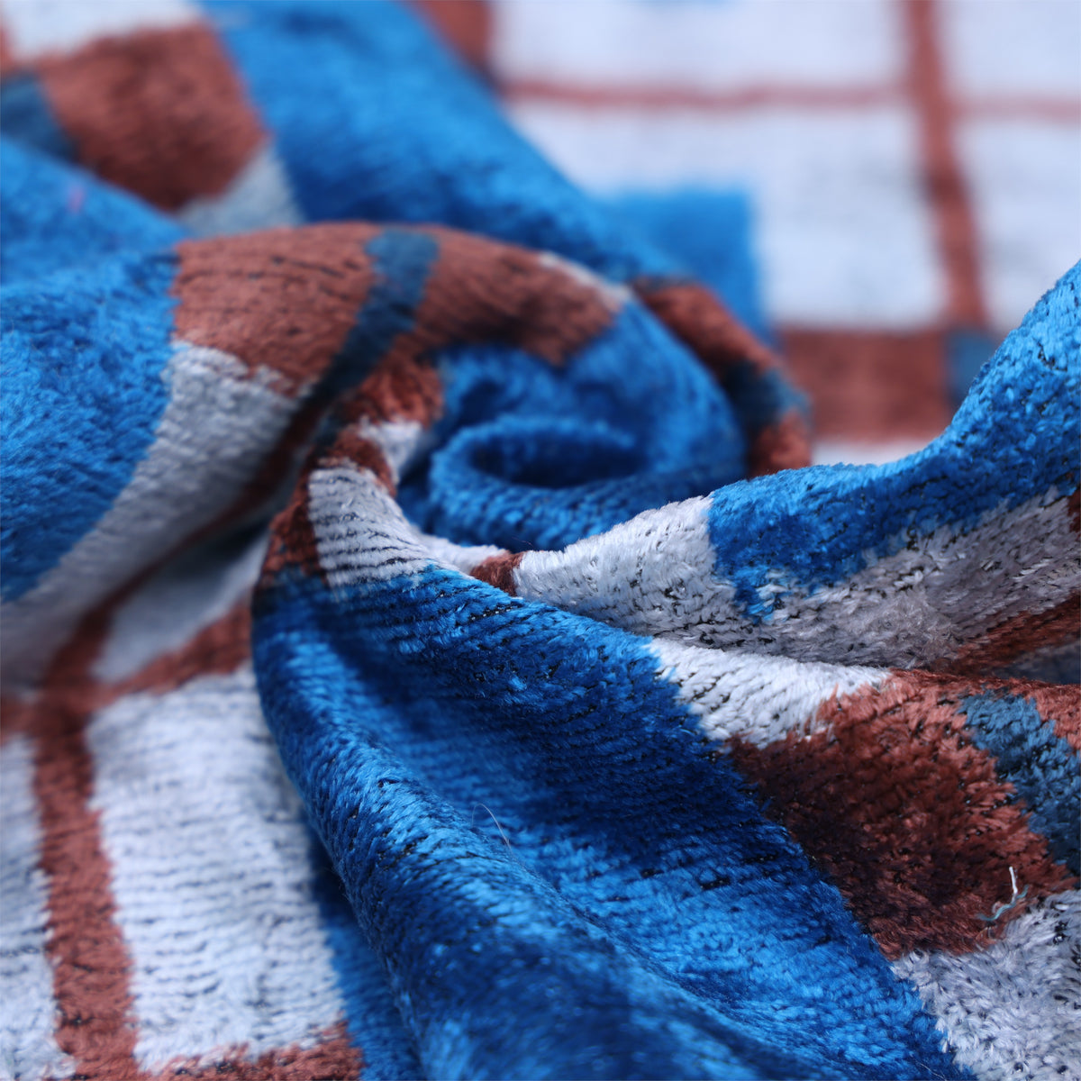 Fabric folds reveal the soft sheen of the cobalt blue and silvery white plaid velvet