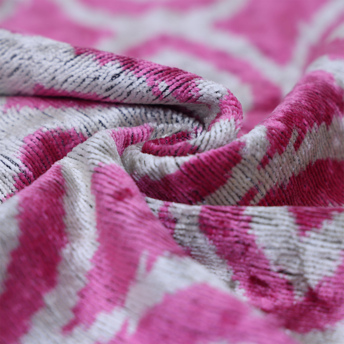 Folded fuchsia pink and silvery white velvet detail showing cut pile and woven ground