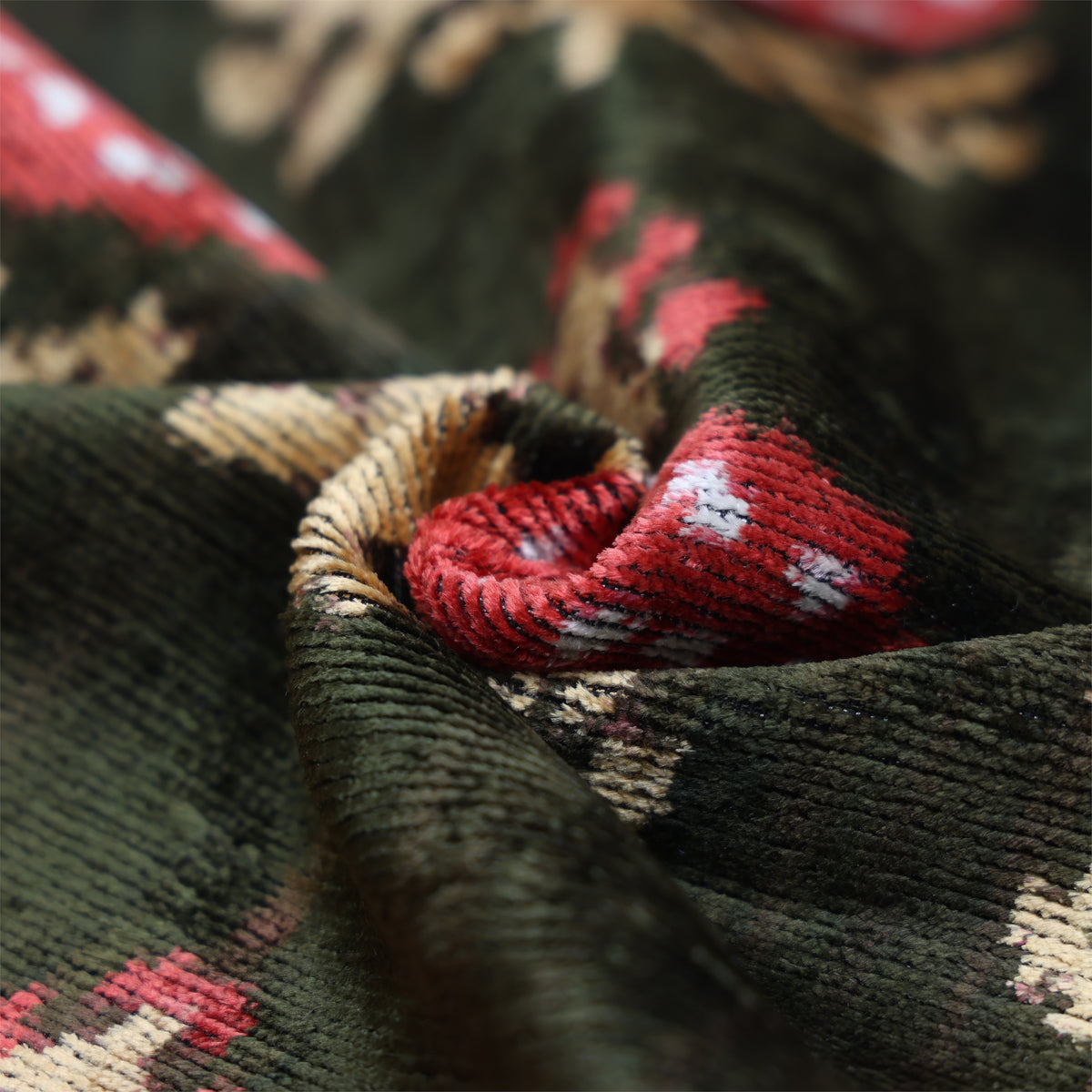 Close-up of dark olive green ribbed silk velvet with crimson red ikat motif