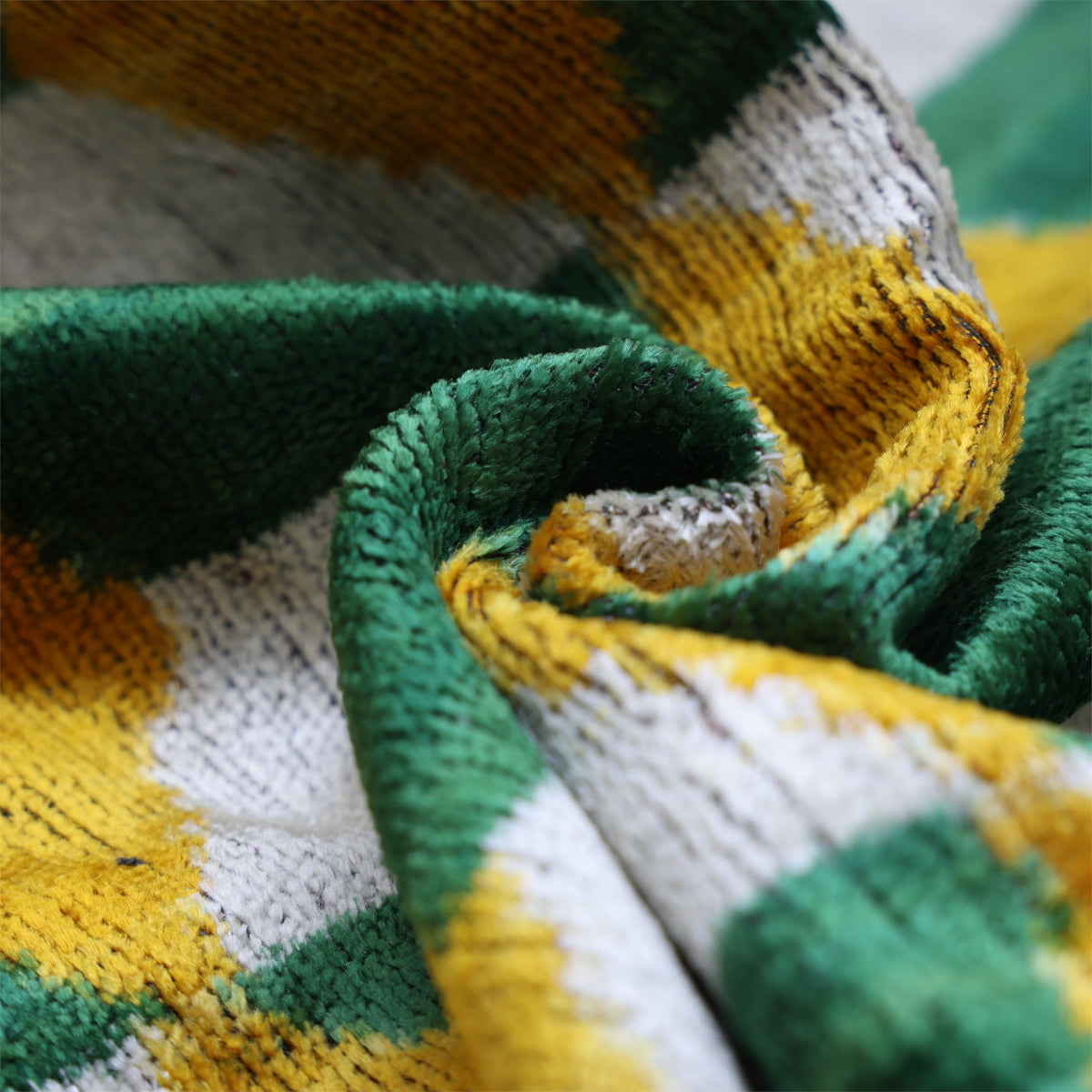 Folded silk velvet showing plush texture in forest green, silvery white and mustard yellow