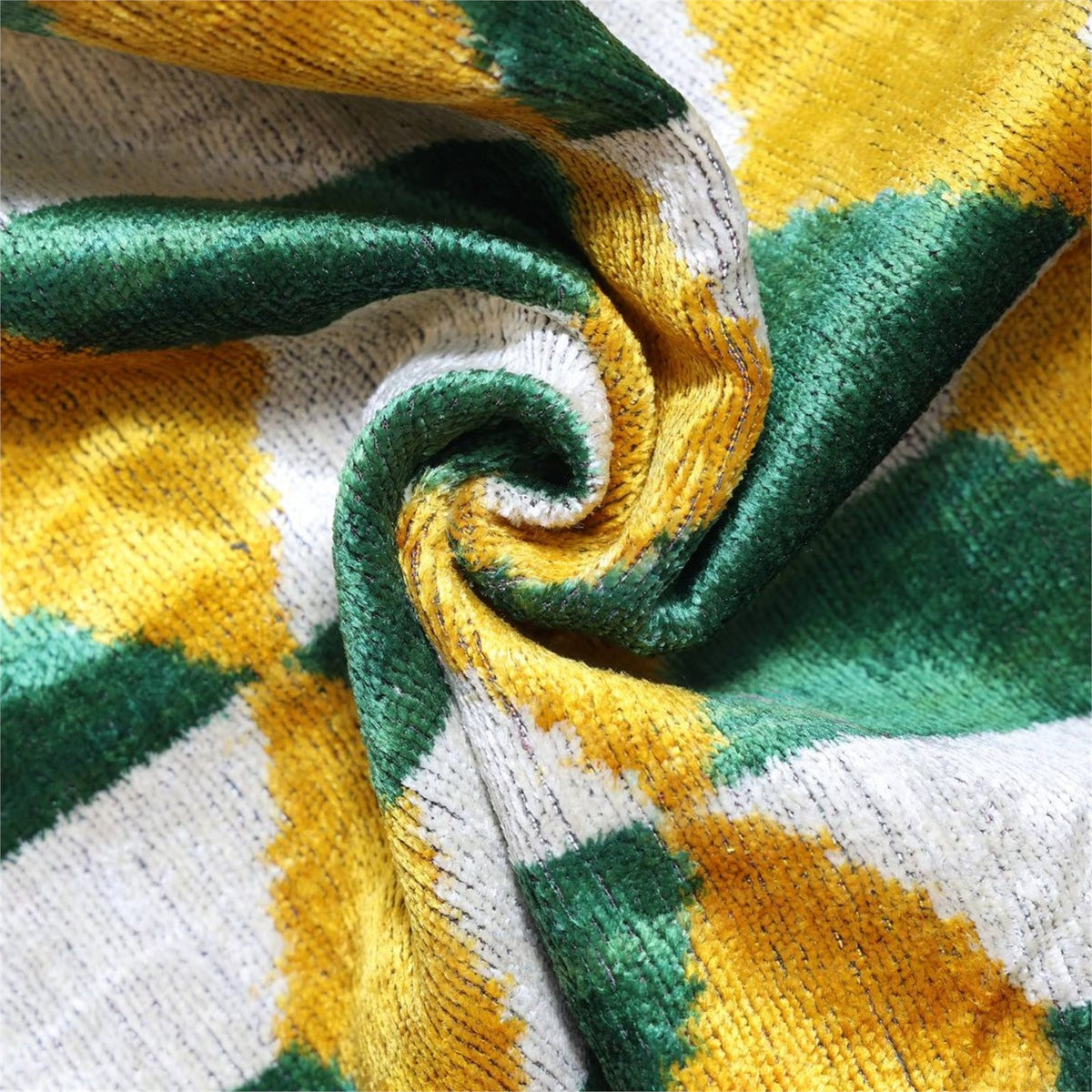Close view of plush forest green velvet pile with silvery white and mustard yellow pattern