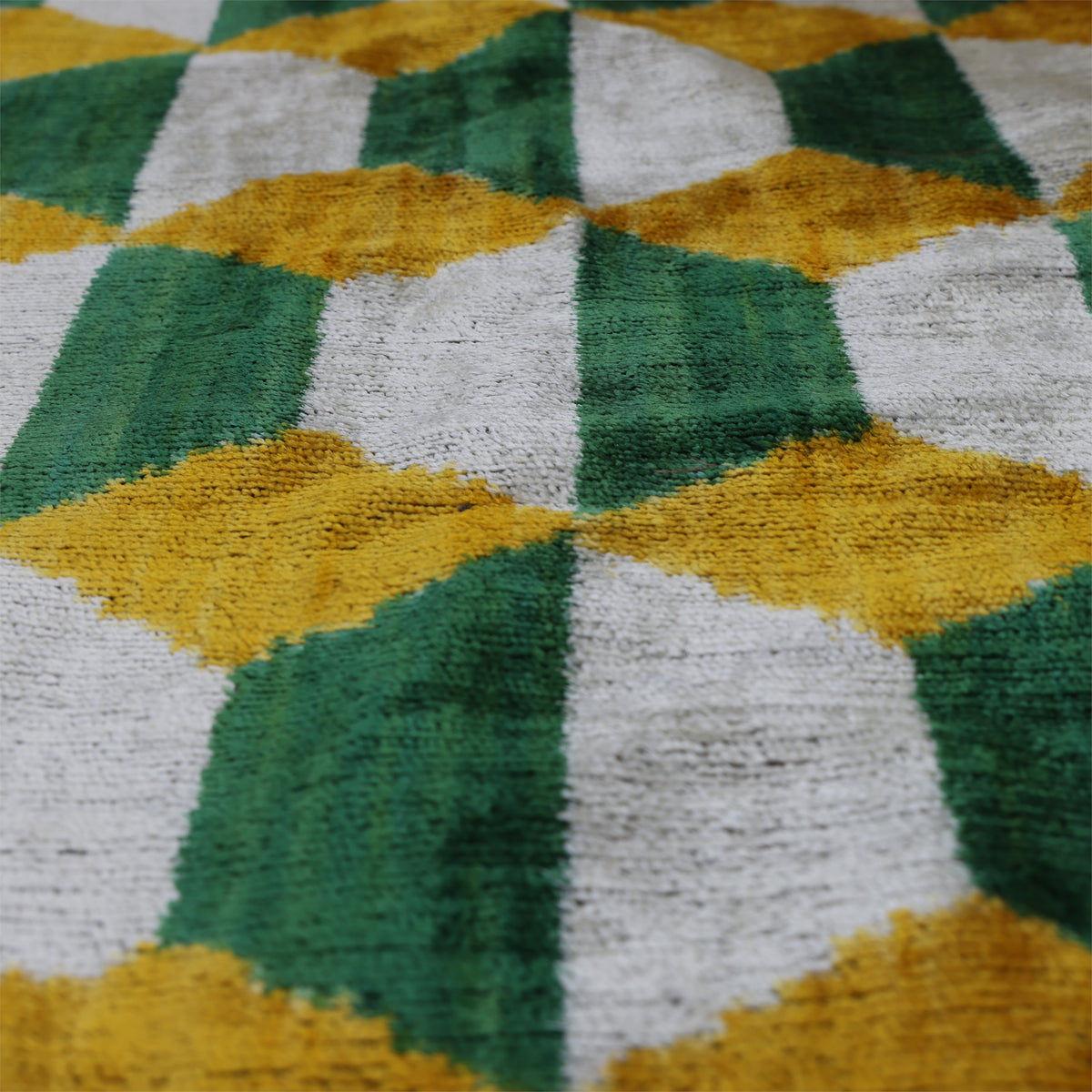 Angled detail of forest green, silvery white and mustard yellow geometric velvet pattern