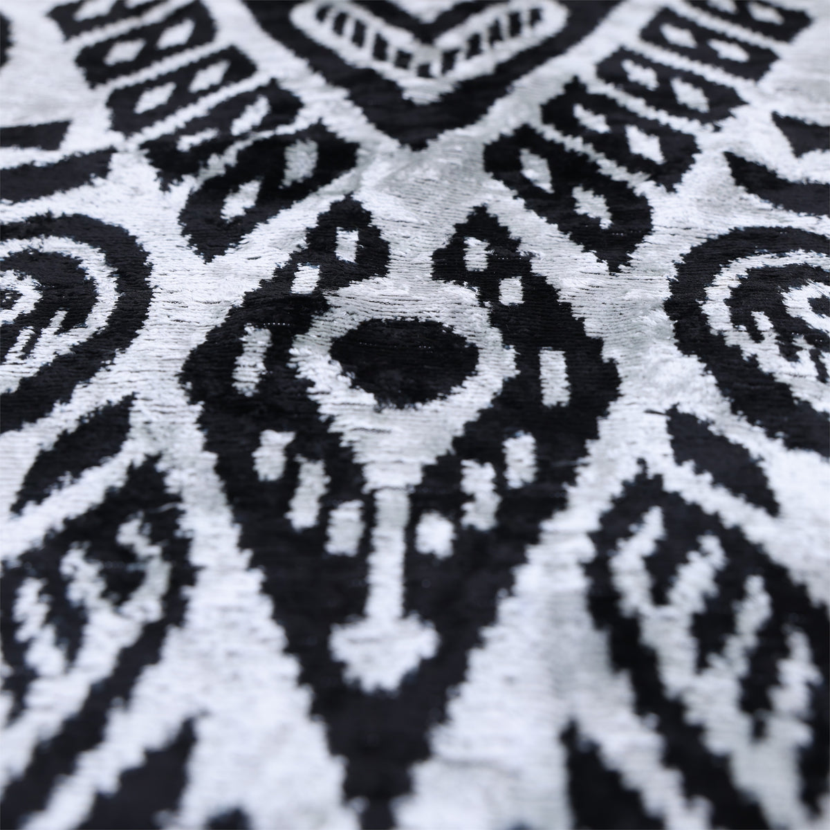 Angled close-up of the center silvery white and jet black ikat motif