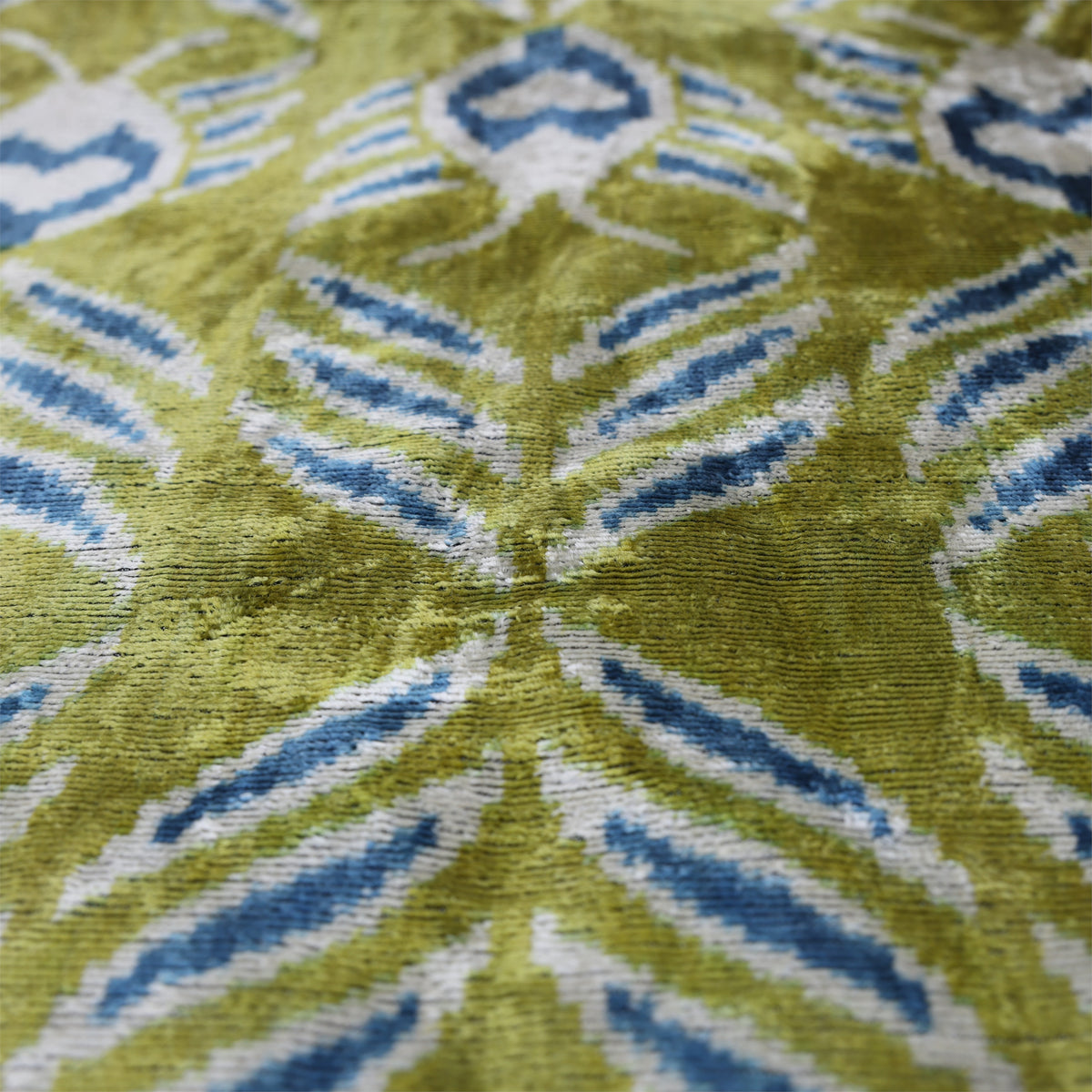Macro view of woven olive chartreuse green and blue ikat velvet texture